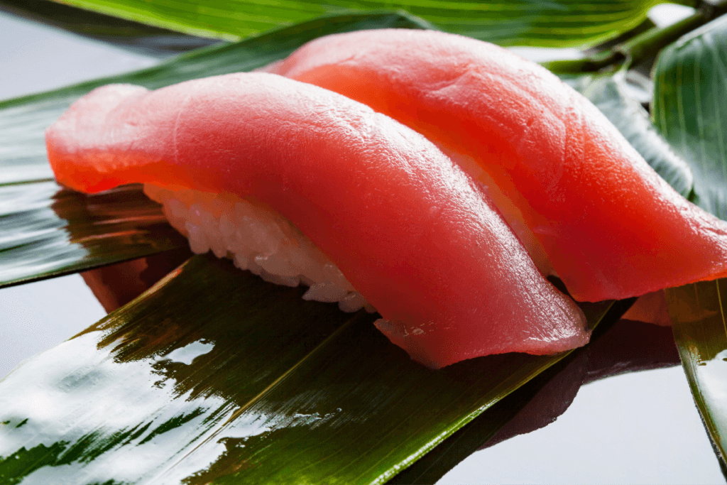 "Close-up of two pieces of fresh tuna nigiri sushi placed on a bamboo leaf, highlighting traditional Japanese cuisine"